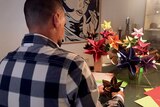 The back of a man making origami flowers.