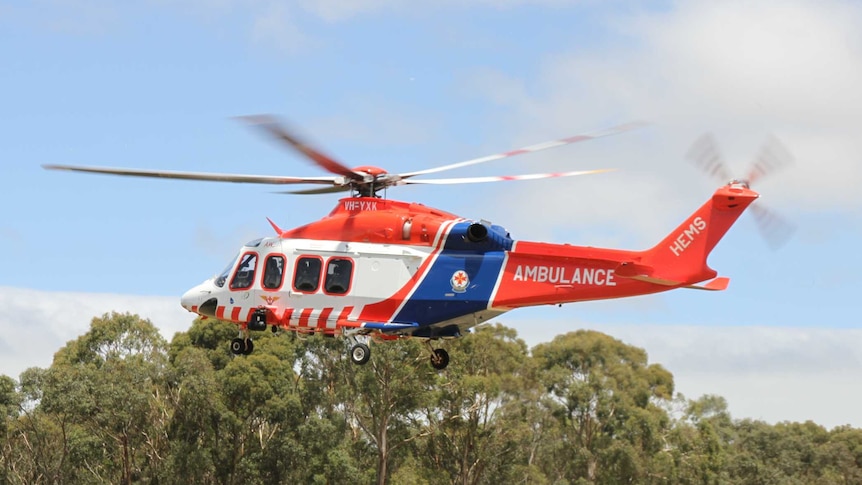 An air ambulance hovers above the ground near the scene of a farm accident.
