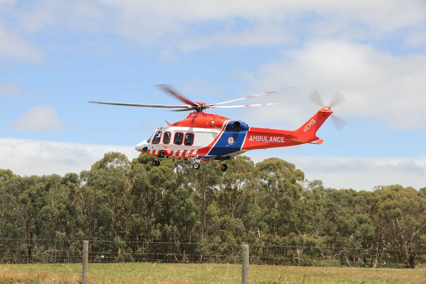 An air ambulance hovers above the ground near the scene of a farm accident.