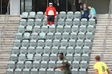 A man wearing a red outfit stands in empty seats during a soccer game