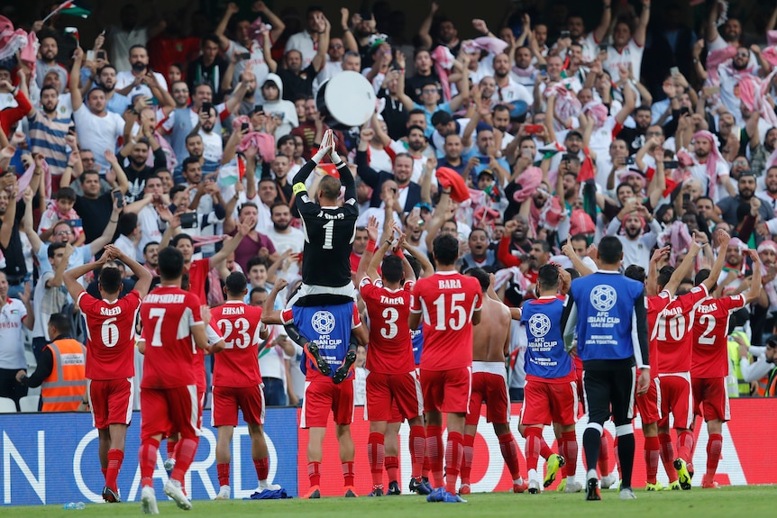 Jordan players lift their goalkeeper on their shoulders to celebrate with spectators after their win over Australia