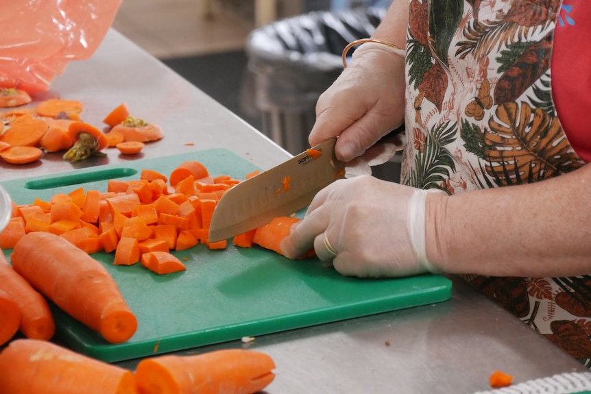 A close up of a woman cutting carrots. 