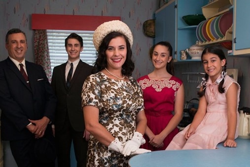 Family wearing period dress in kitchen.