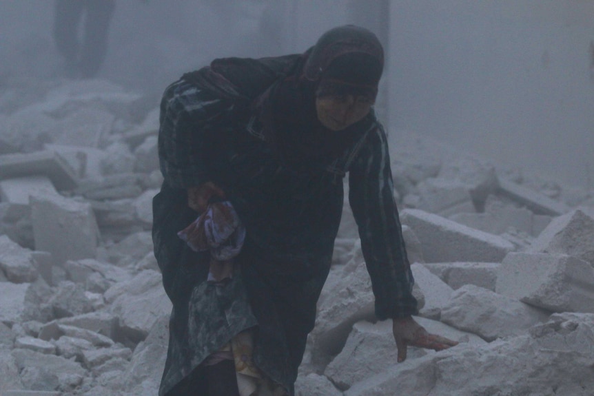 An injured woman walks at a site hit by an airstrike in the rebel-held al-Ansari neighbourhood of Aleppo, Syria