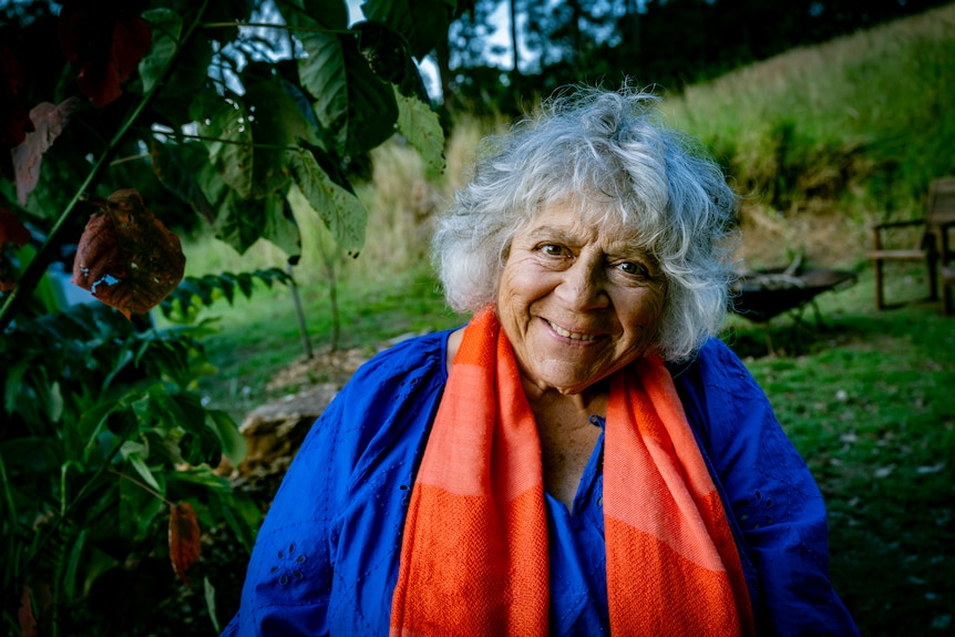 Woman smiling to camera with rural background.