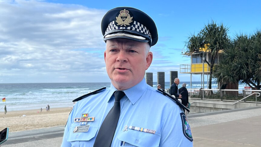 A police officer with a hat on stands by the beach in Surfers Paradise