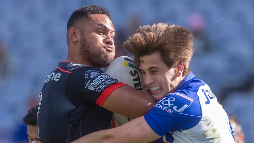 David Fusitua is wrapped up in a tackle by Lachlan Lewis.