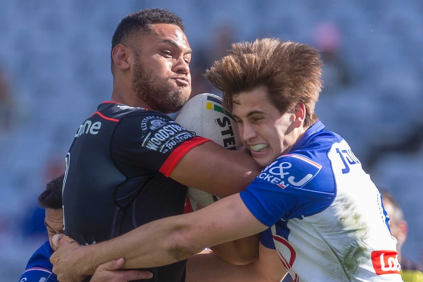 David Fusitua is wrapped up in a tackle by Lachlan Lewis.