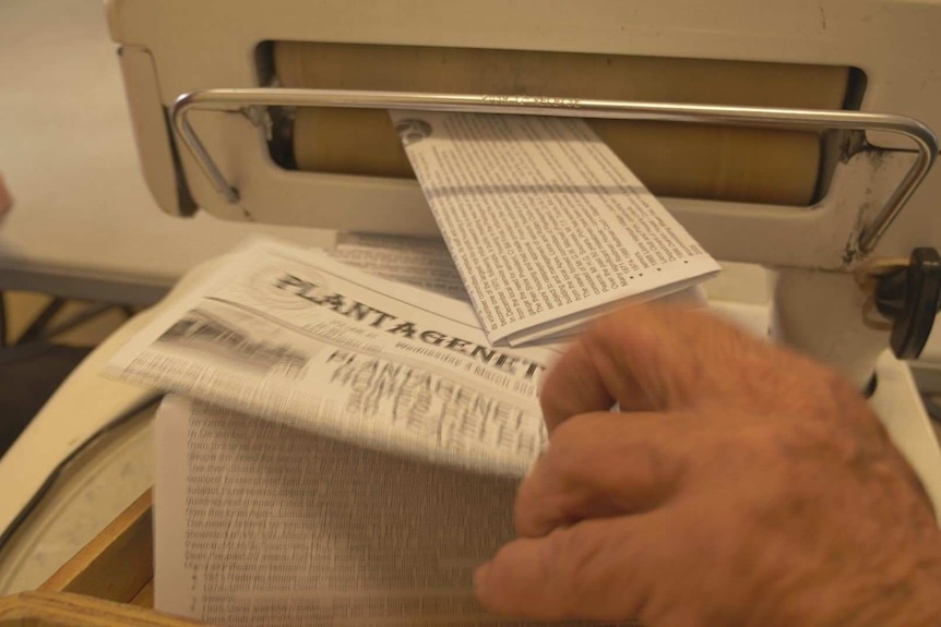 Newspapers coming out of a pressing machine.