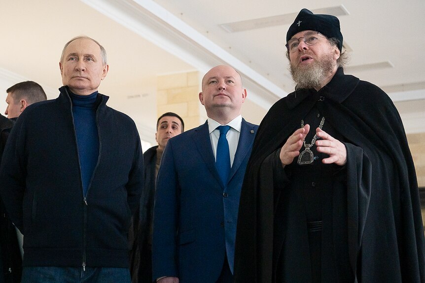 Vladimir Putin (left) and Sevastopol governor (centre) listen to metropolitan of Pskov speaking.