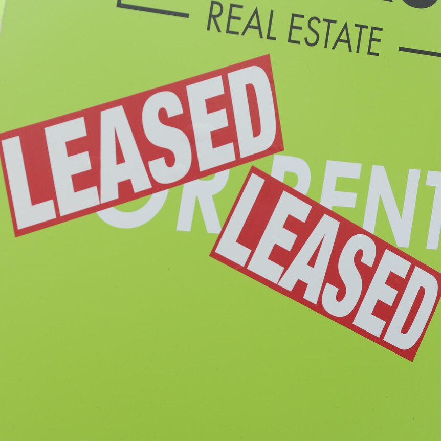 A green 'for rent' sign with LEASED stickers stuck on it. 