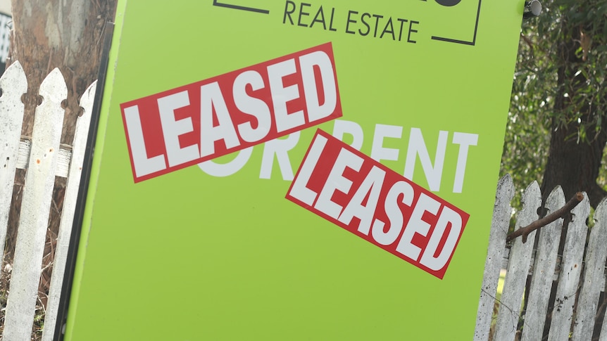 A green 'for rent' sign with LEASED stickers stuck on it. 