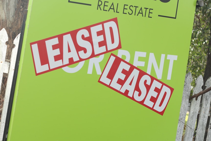 A green 'for rent' sign with LEASED stickers stuck on it. 