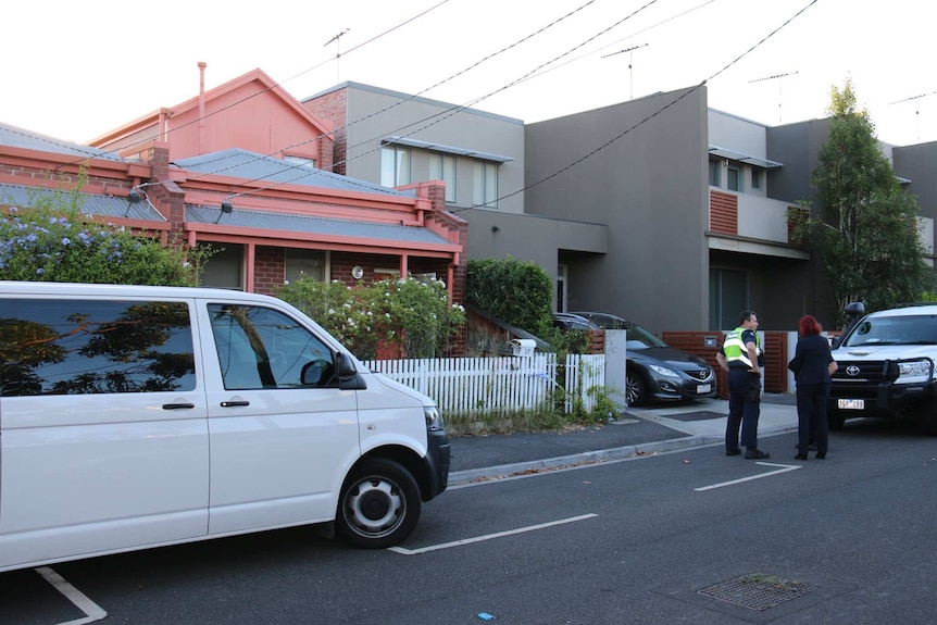 Several police officers stand outside a house.