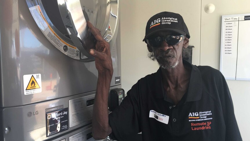 Barunga resident Freddy Scubby opening a washing machine at the laundry.