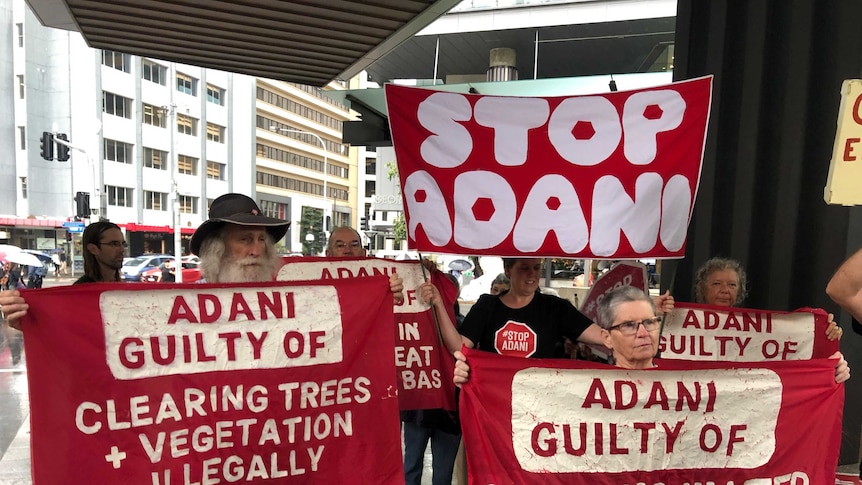 Protesters hold up signs outside Brisbane Magistrate Court.