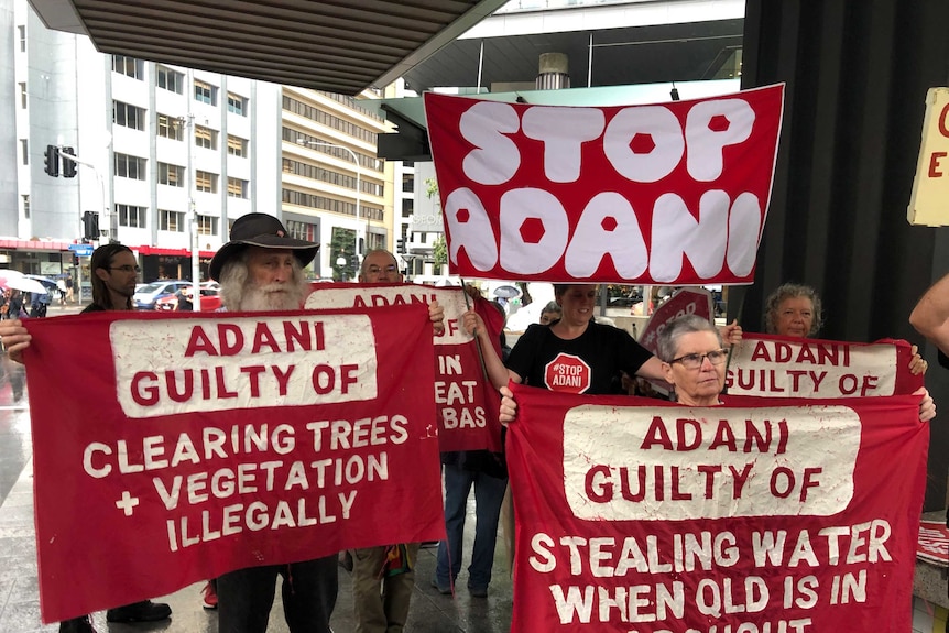 Protesters hold up signs outside Brisbane Magistrates Court.