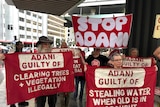 Protesters hold up signs outside Brisbane Magistrate Court.