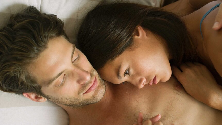 A woman laying on a man's chest in bed