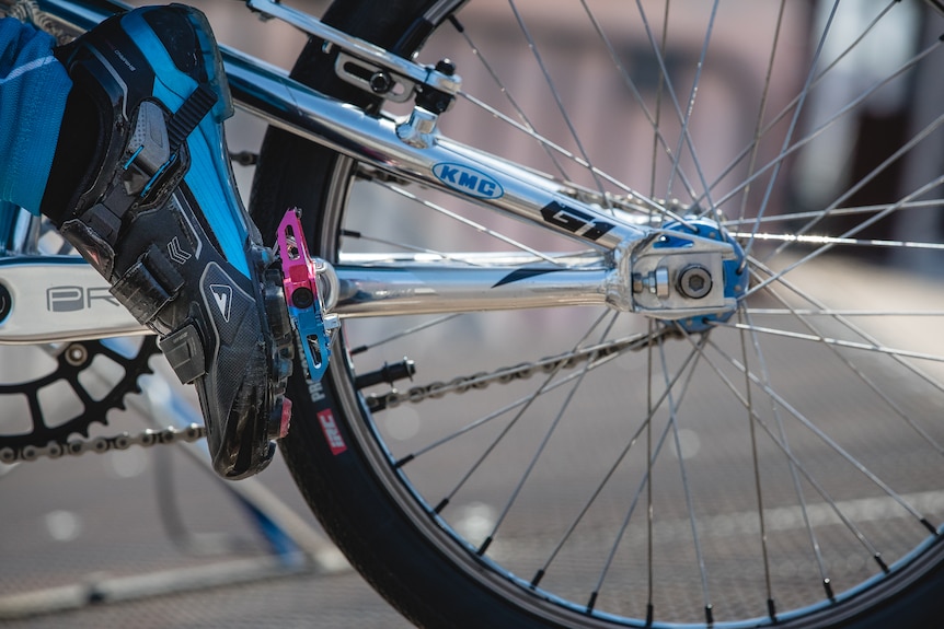 A picture of a back wheel and a boot on a pedal.