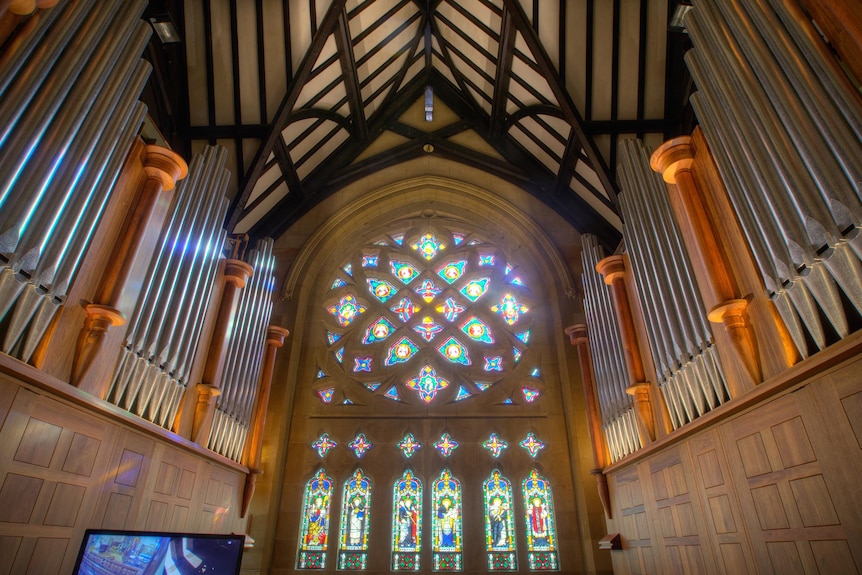 The inside of a church, including stained glass windows and the pipes of an organ.