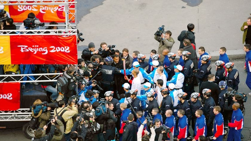 The Olympic flame is surrounded by security in Paris