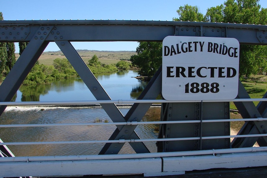 A sign attached to the side of a steel bridge.