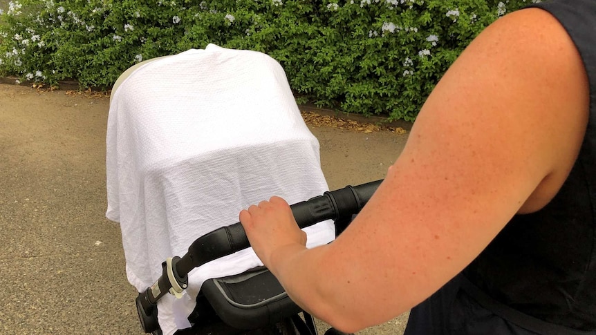 A woman demonstrating putting a blanket over a pram