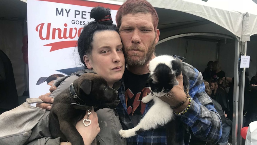 A man and woman, holding a puppy and kitten