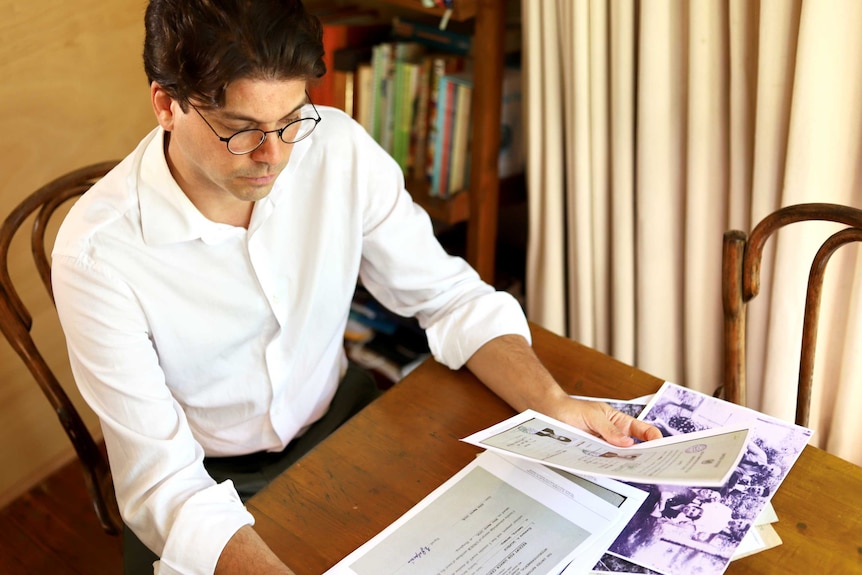 A man sits at a table, reading documents.