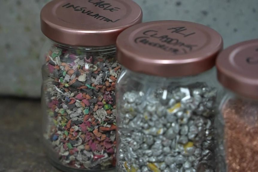 three glass jars with fragments of brightly colored materials inside. 