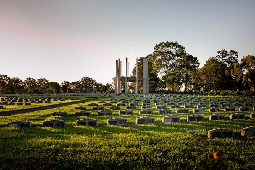 Graves with small headstones surround a large circular monument.