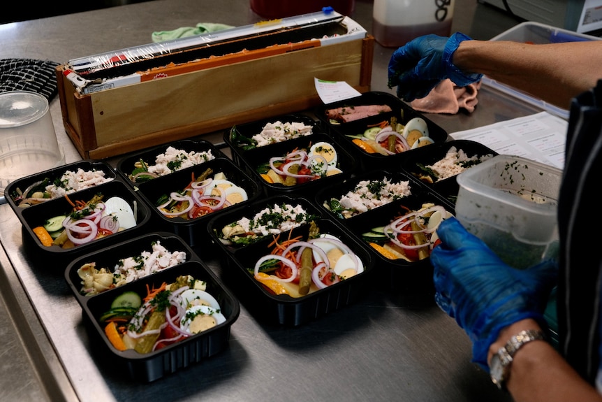 Boiled eggs, pickles and salad being prepared by a Meals on Wheels volunteer. 