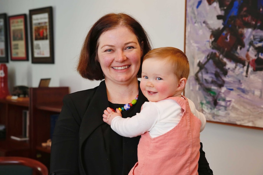 Lisa Chesters smiles while holding her daughter in her office