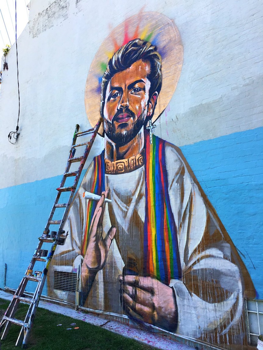A mural on a house depicts singer George Michael as a saint with a rainbow halo.