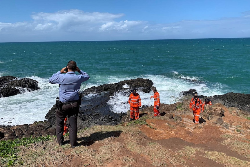 Police and the SES searching rocks on the oceanfront
