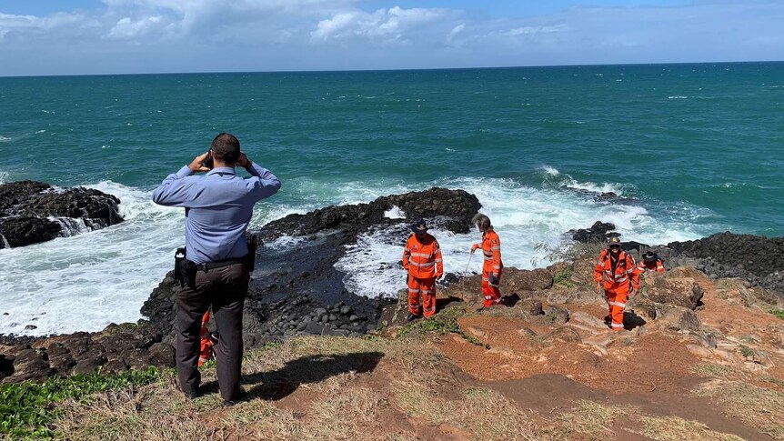 Police and the SES searching rocks on the oceanfront