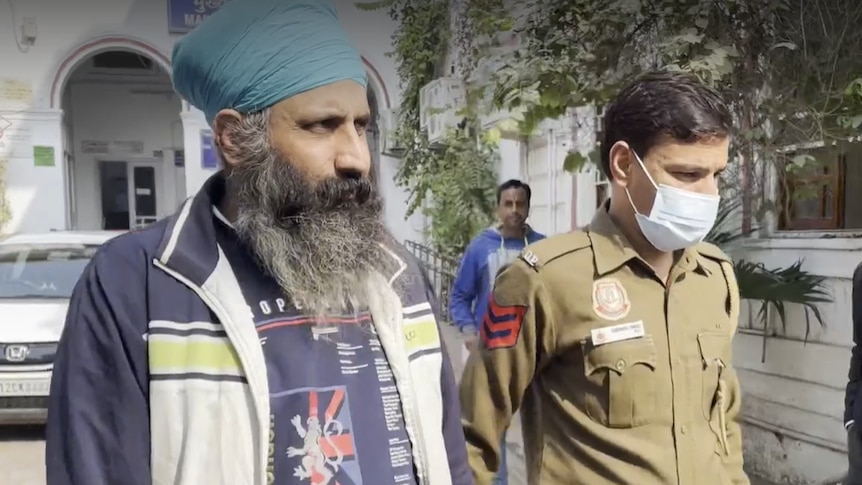 Rajwinder Singh walks into court holding hands with a security guard.