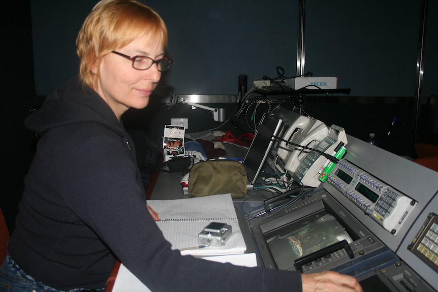 Woman in TV control room pushing buttons.