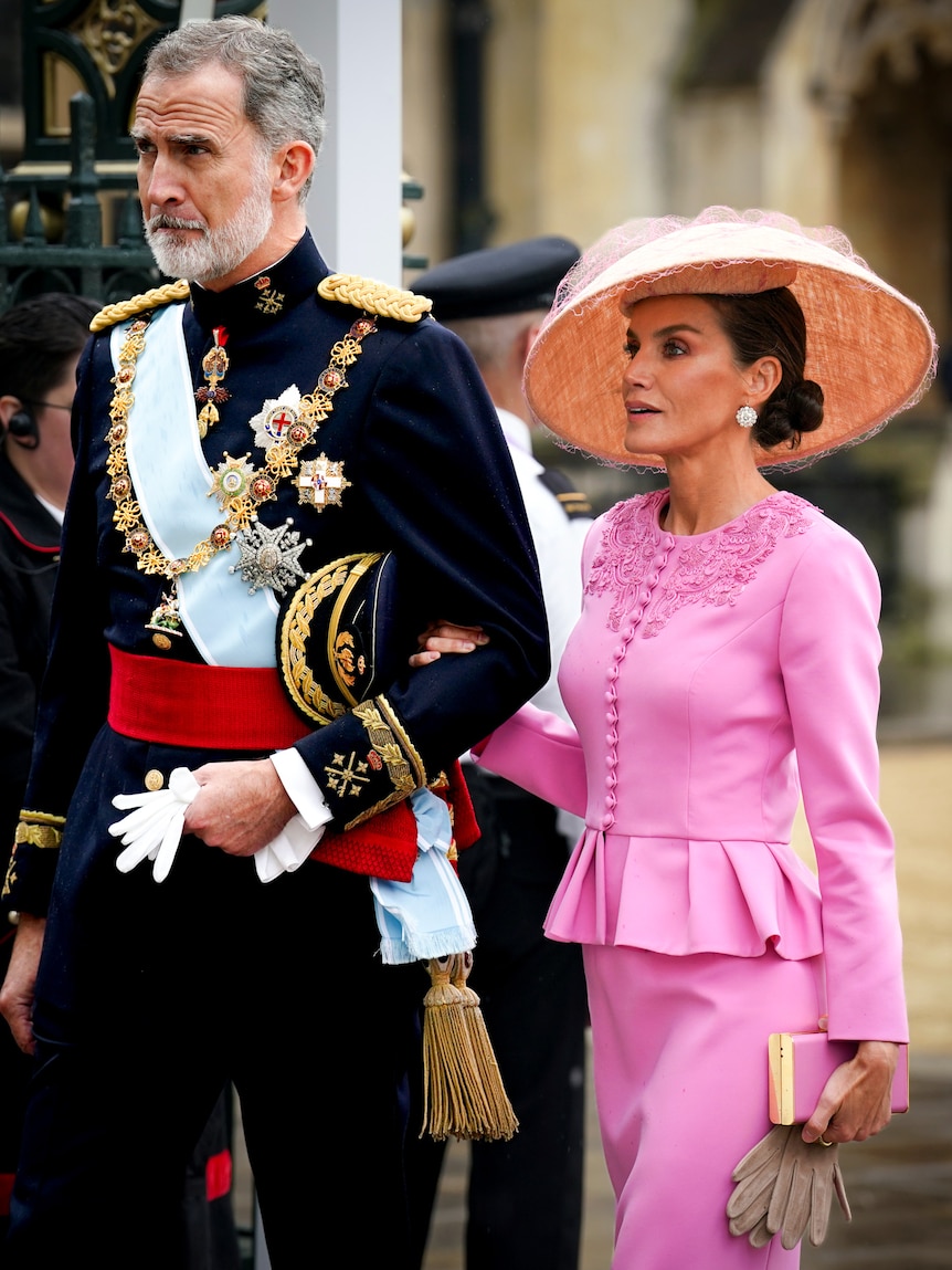 A man in military dress and a woman in a pink suit and hat