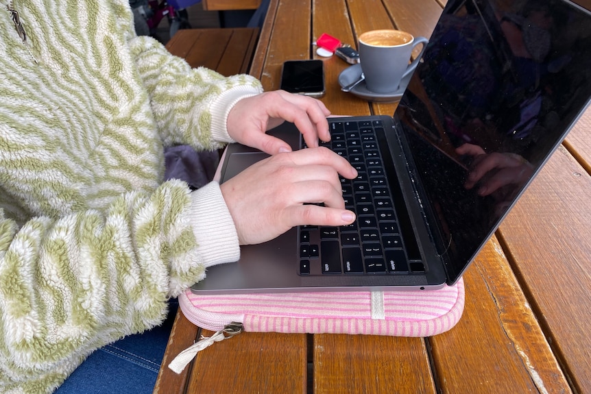 A young woman's hands operating a laptop.