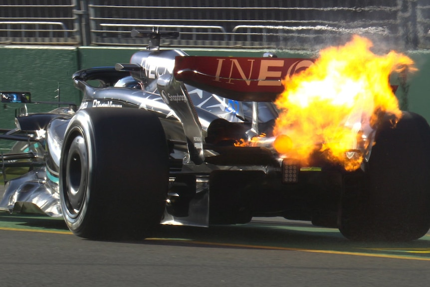 The Mercedes F1 car stopped on track with fire coming from its rear.