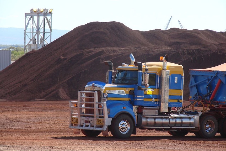 A truck in front of an ore stockpile.