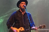 Jim Moginie plays guitar and sings on stage
