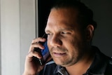 CAAMA Station Manager Gilmore Johnston wearing a blue shirt talking on iPhone