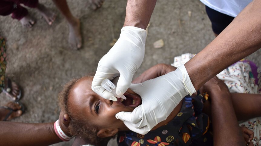 A child receives a dose of oral medicine at the launch of a polio vaccination drive in Papua New Guinea.
