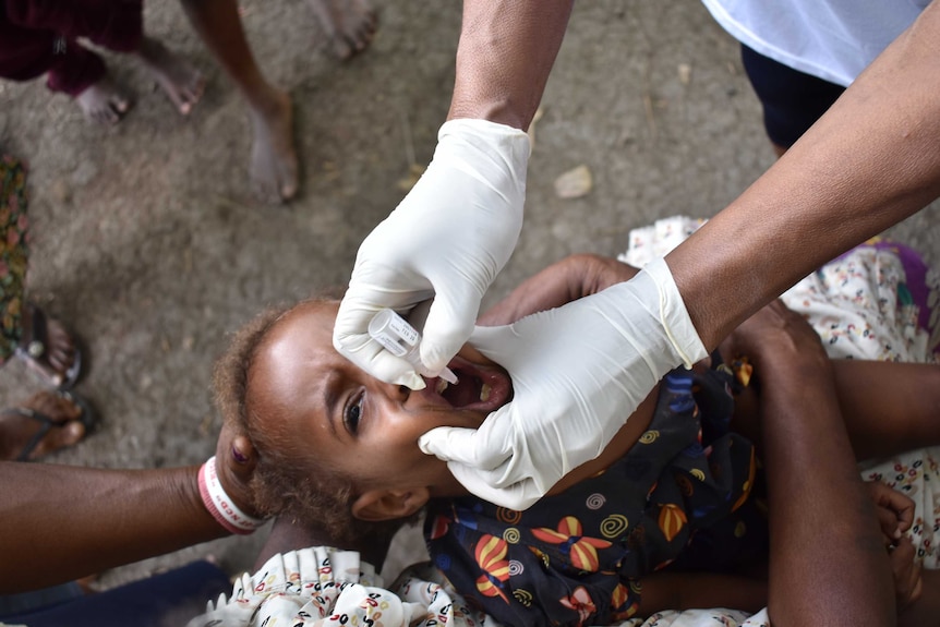 A child receives a dose of oral medicine at the launch of a polio vaccination drive in Papua New Guinea.