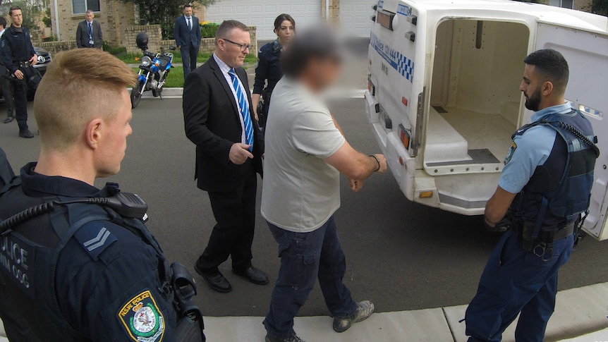 A man is led away by police officers