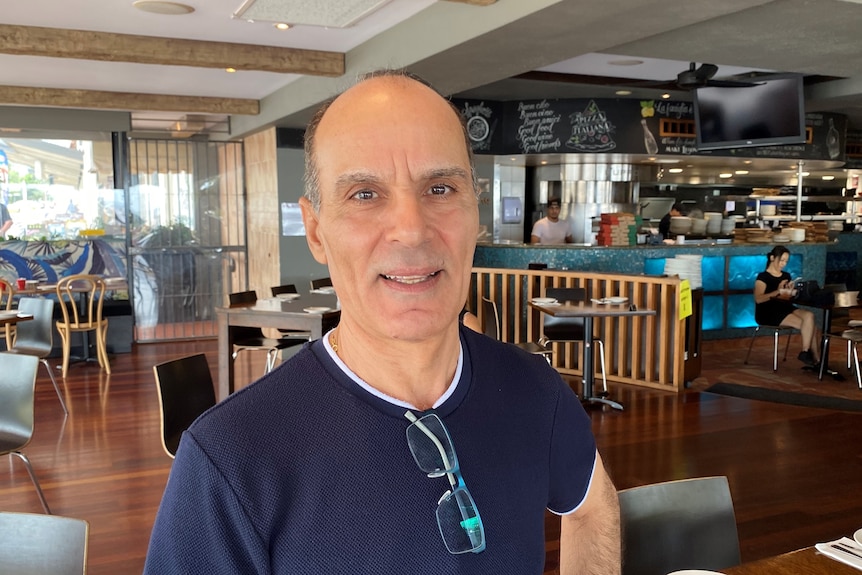 A restaurant owner stands in his restaurant