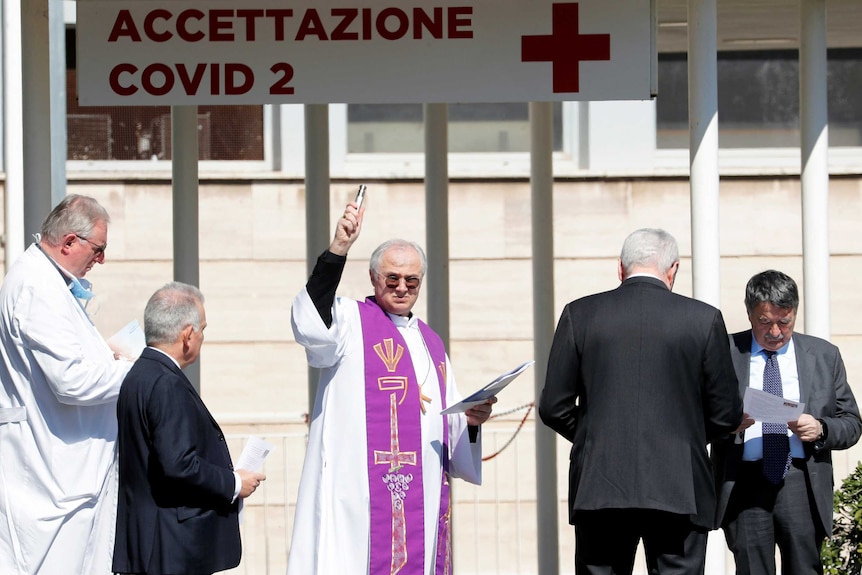 A priest sprinkling holy water at a hospital